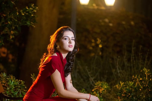 Night portrait photography in Budva Old Town: Woman in red dress seated on vintage bench, Budva