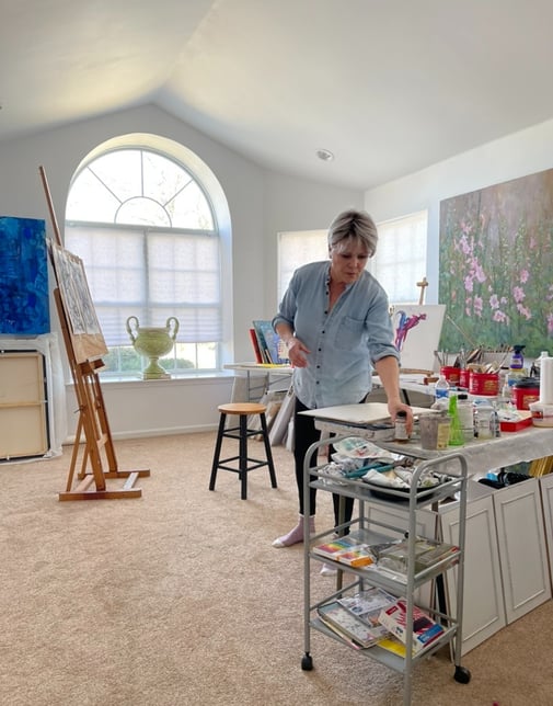 a woman in a blue shirt is standing in front of a painting