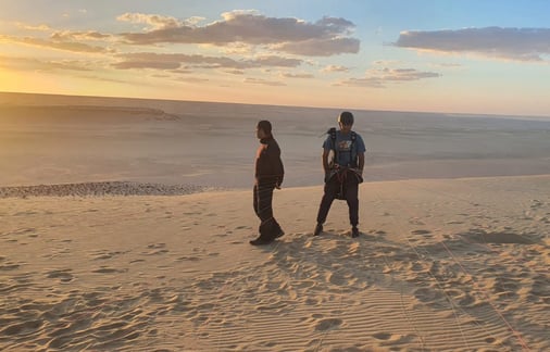 two people standing on a sand dune paragliding egypt