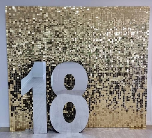 18 mirror infinity marquee number sitting in front of a gold shimmer wall in Brisbane before being turned on.