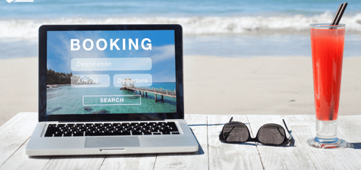 a laptop with an open booking page and a drink