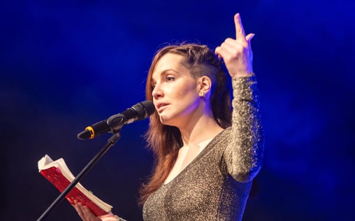 Britta Kah auf der Bühne. Poetry Slammerin mit rotem Buch