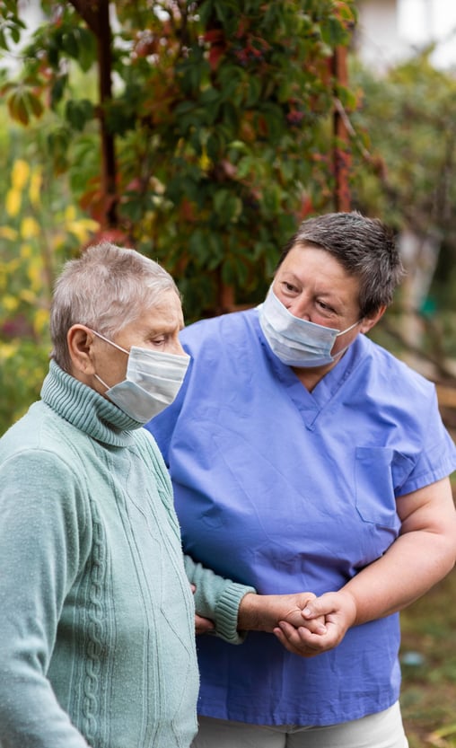 Socio sanitario ayudando a persona mayor a andar con mascar