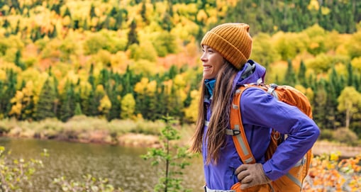 Happy lady sideways with orange backpack and yellow trees in the background