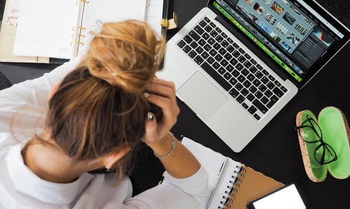 a woman sitting at a desk with a laptop and a notebook