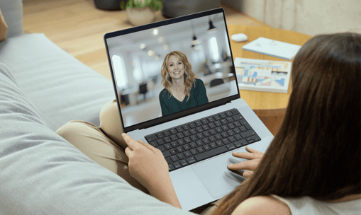 a woman sitting on a couch with a laptop computer screen showing a video chat
