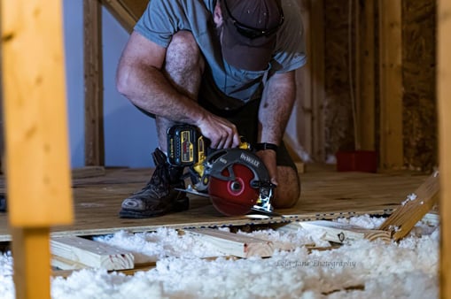 Handyman using a circular saw to cut subflooring during floor framing repair