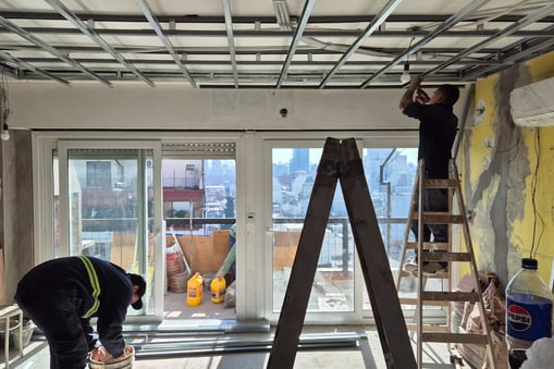 a construction worker fixing the electrical conduits in the ceiling