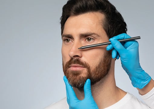 Wireframe nose on man's face, gloved hand touches, symbolizing surgical planning.