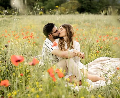Editorial engagement photo of a couple kissing in a Provence poppy field by a fine art photographer