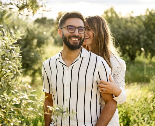 Provence couple session in olive grove — she whispers in his ear, laughing, in fine art style