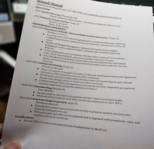 a person holding a paper with Sennad Ahmad's  resume