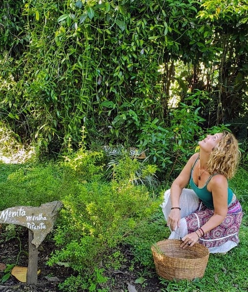 a crouching woman holding a basket in the middle of nature and looking upwards
