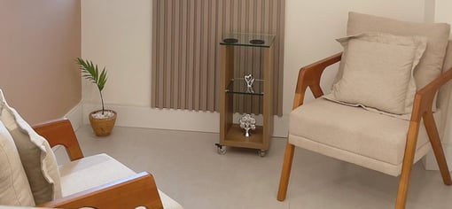 Foto do consultório de psicologia da psicóloga Laura Maria, duas poltronas e fundo de madeira.