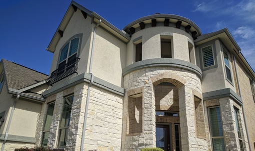 A two story beige stone brick home sparkling and spotless after receiving window cleaning services