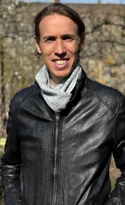 Photo of Chris, Wellbeing and health coach South Wales, standing outside in the sun wearing leather jacket