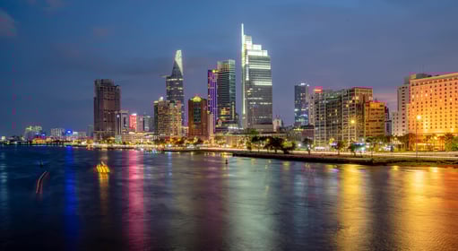 a city skyline with a river and a boat in Ho Chi Minh City, Vietnam