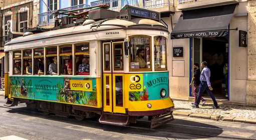 a trolley car with people walking down the street in Lisbon, Portugal