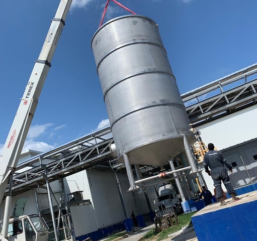 a crane lifts a large metal tank into place