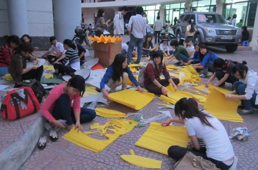 a group of people sitting on the ground with yellow paper