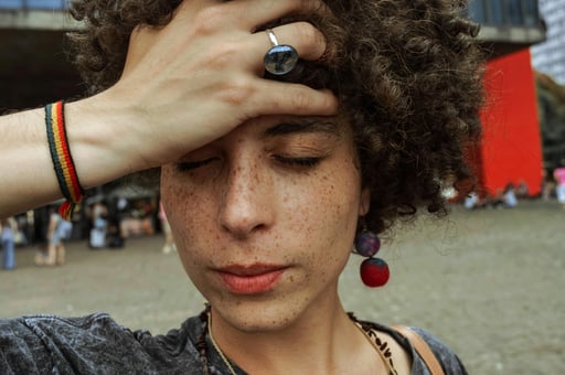 A close-up of a stressed person looking at the mirror, noticing acne breakouts and hair thinning. Th