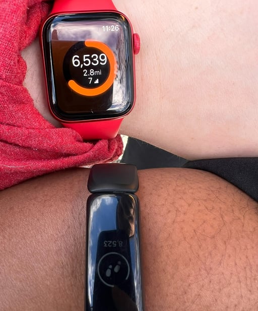 two people wearing a red and black watch on their wrist.