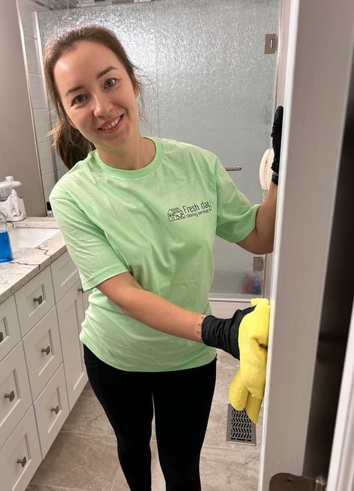 a woman in a green shirt is cleaning a bathroom