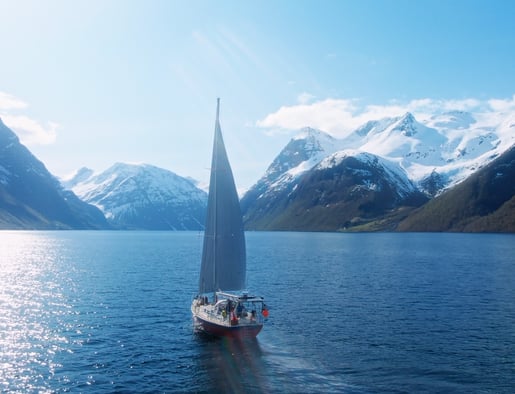 a sailboat sailing on a fjord with mountains in the background | ski and sail in the Lyngen Alps