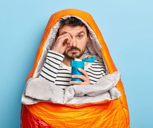 a man in a sleeping bag with a coffee flask