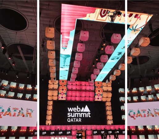 A vibrant stage setup at Web Summit Qatar with colorful LED displays and intricate lighting design.