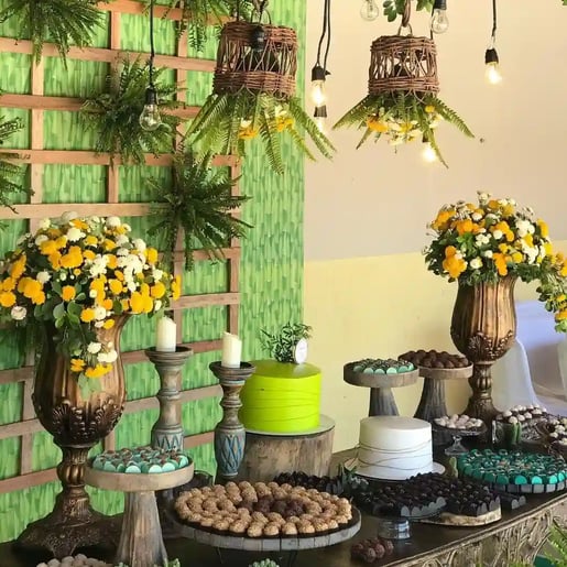 Decoração de festa com flores e doces dispostos em mesas decoradas em estilo rústico, ideal para cel