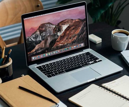 Laptop on a desk with notebooks and coffee
