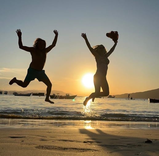 two children jumping in the air at sunset