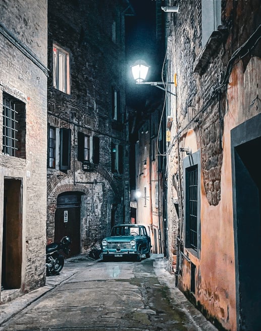 Photo of a vintage Italian car in an alley at night in Perugia, Italy.