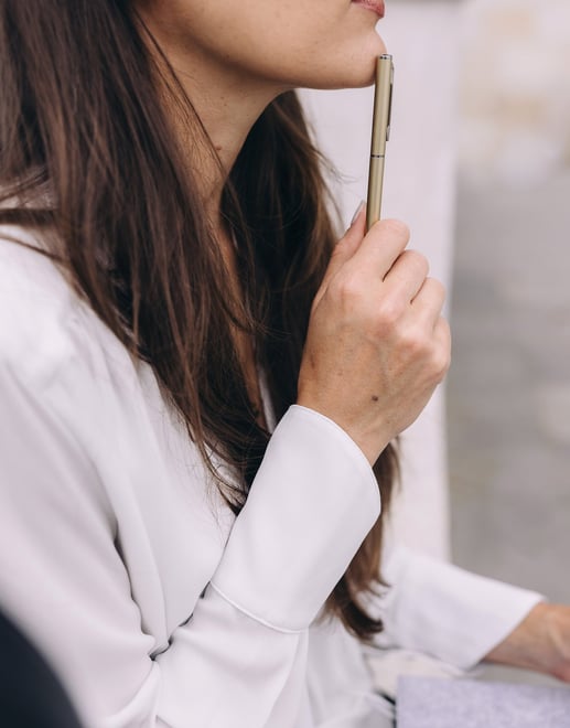 a woman touching her chin with the pen in her hand