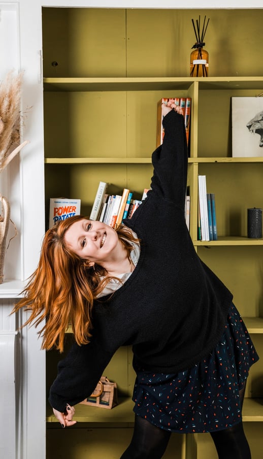Femme rousse prenant une pose naturelle dans une bibliothèque