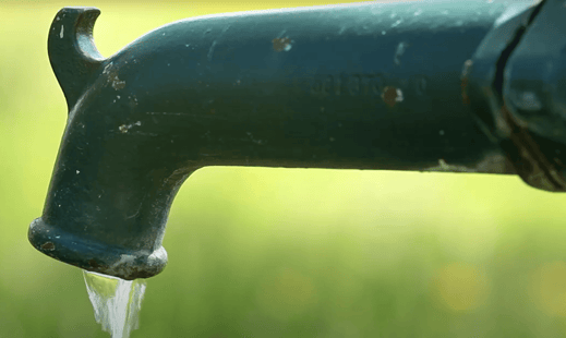 Rustic green outdoor faucet with water flowing