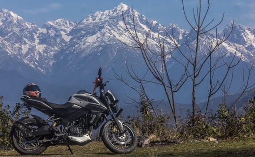 a motorcycle parked on a grassy field with mountains in the background