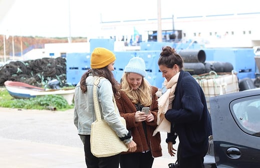 three women standing in front of a car