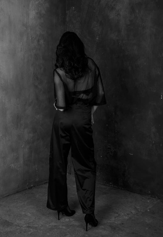 The back of a stylish brunette woman in all black wearing and in black heels