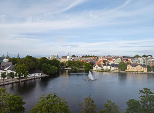 Lake and small waterfall with houses in background in Stavanger Norway