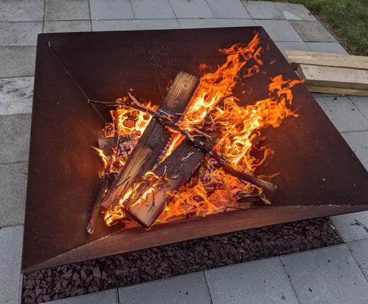 a square steel firepit with a large fire burning inside