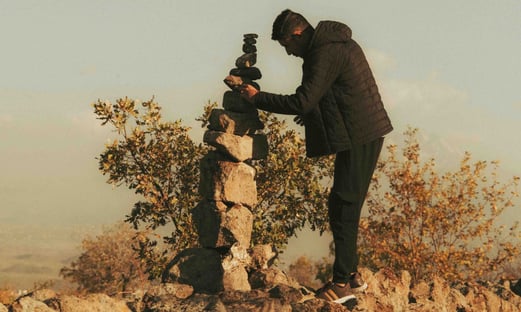 a man trying to build something by putting smaller rock in the top of bigger rock