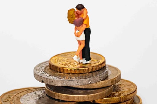 a couple kissing on top of a pile of coins