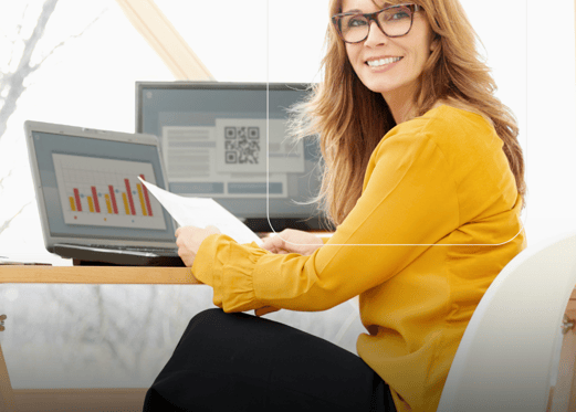 a woman sitting at a desk with a laptop and a laptop