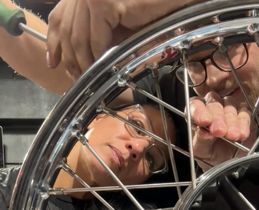 woman and man lacing a motorcycle wheel