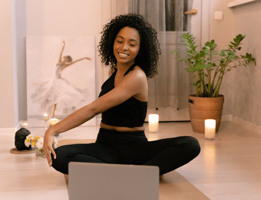 a woman sitting on a yoga mat with candles and candles engaging in virtual physiotherapy exercises
