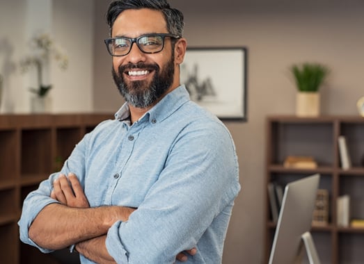 a man with a beard and glasses on his arms crossed and smiling
