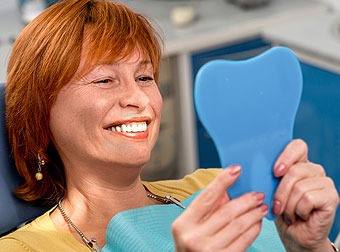Smiling woman looking her smiling face in a mirror