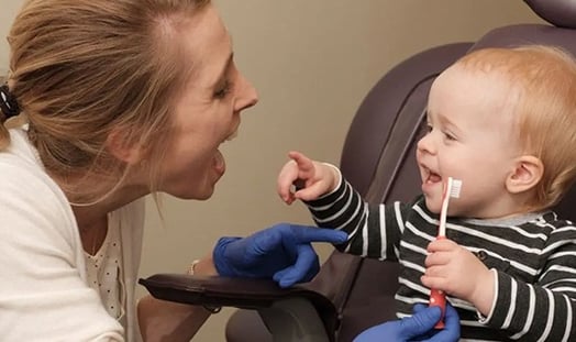 Child holding tooth brush with dentist